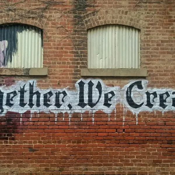 A vibrant graffiti mural on a brick wall with the words 'Together We Create,' symbolizing collaboration and creativity.